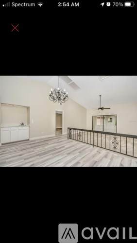 A room with a chandelier and a balcony with a railing.