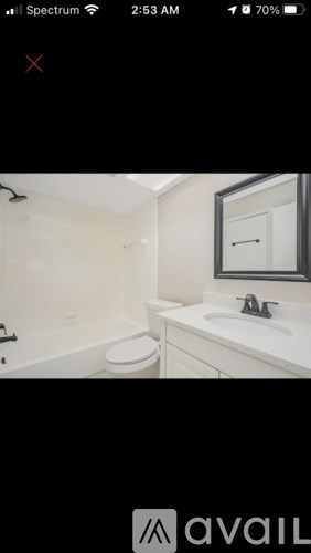 A white bathroom with a toilet, sink and mirror.