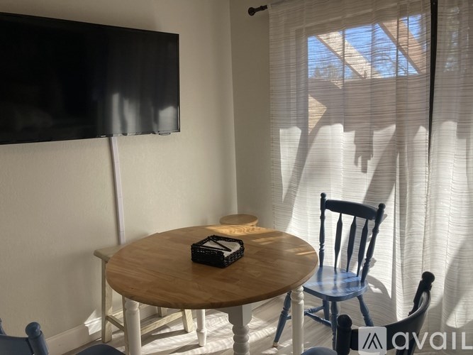 A black TV is mounted on a white wall above a wooden table with a black box on it.