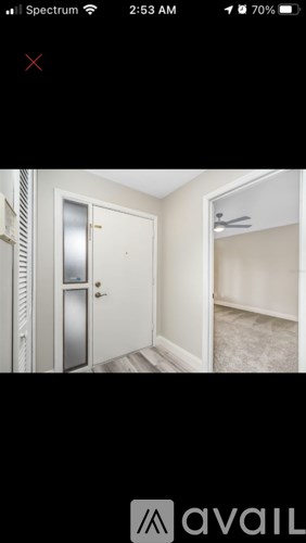 A white door is in a room with a fan on the wall.