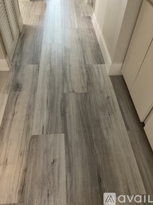 A long hallway with wood flooring and white walls.