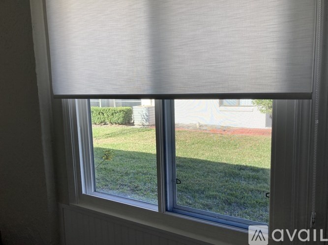 A window with a view of a green lawn and a house.
