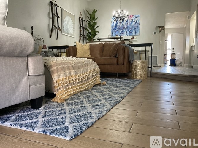 A living room with a brown couch and a blue patterned rug.