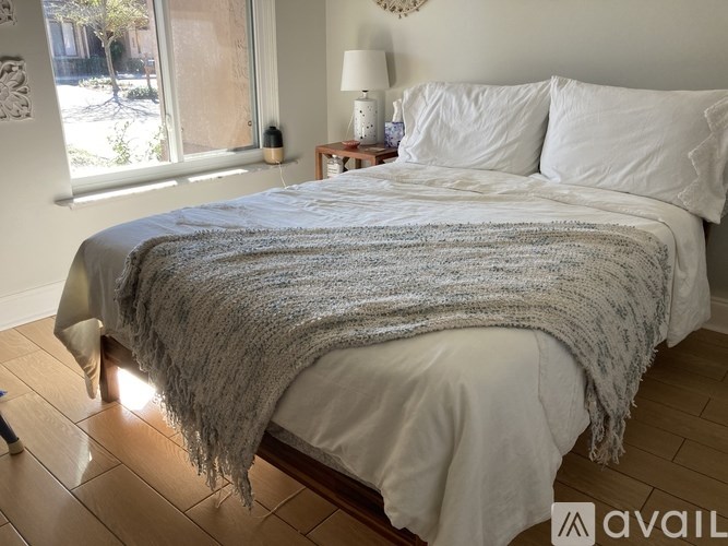 A bed with a grey blanket and white pillows in a room.