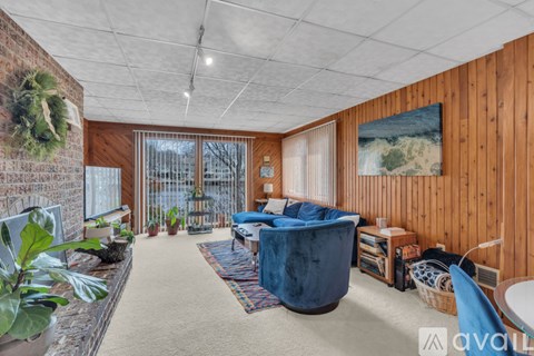 A living room with a blue sofa and a wooden wall.