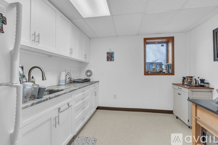 A kitchen with white cabinets and a window.