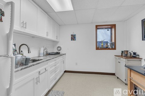 A kitchen with white cabinets and a window.