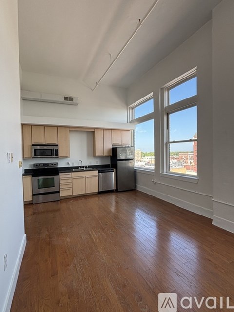 A kitchen with wooden floors and a large window overlooking a cityscape.