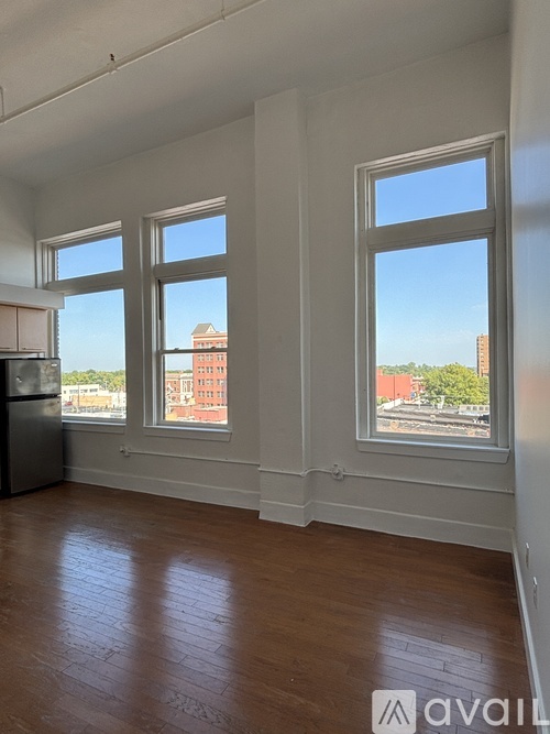 A room with three windows overlooking a cityscape.