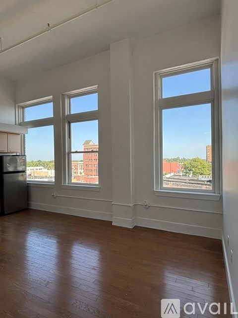 A room with three windows overlooking a cityscape.