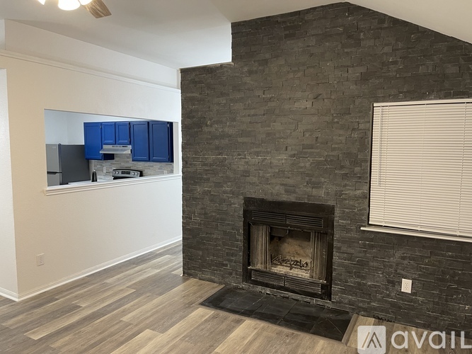 A living room with a fireplace and a kitchen area in the background.