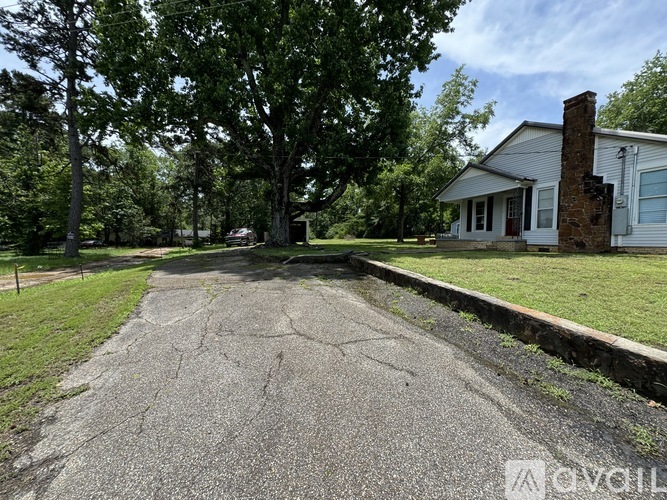 A driveway leads to a white house with a brick chimney.