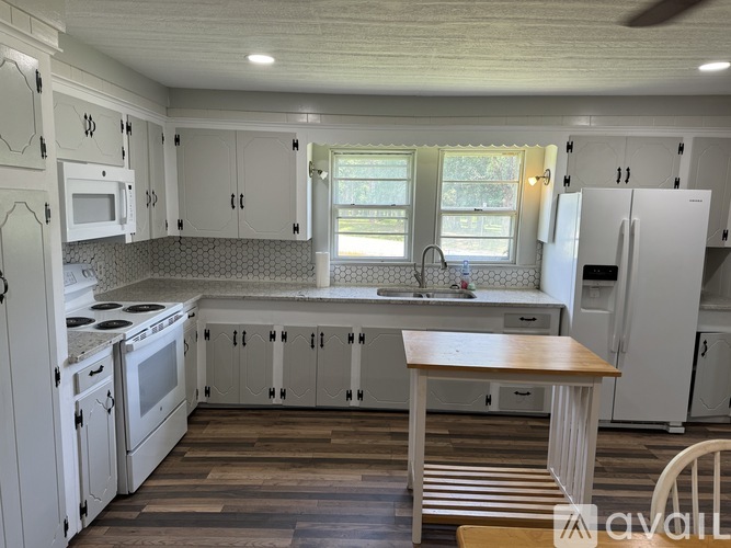 A kitchen with white cabinets and a wooden table.