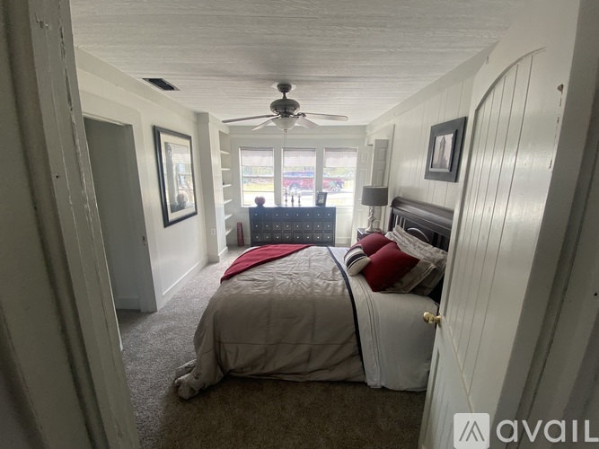 A bedroom with a bed, a ceiling fan, and a window.