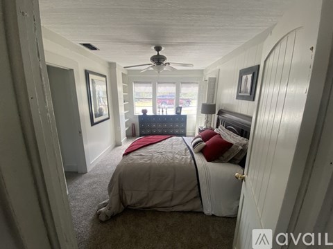 A bedroom with a bed, a ceiling fan, and a window.
