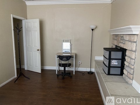A room with a desk, chair, and a fireplace.