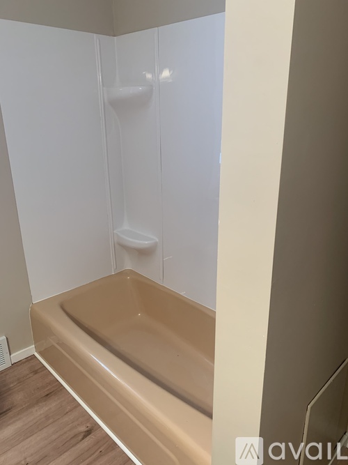 A white bathroom with a beige tub and a white toilet.