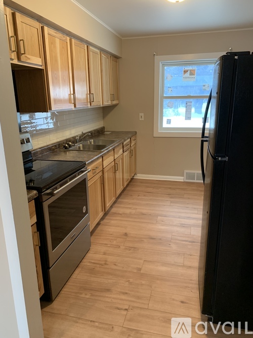 A kitchen with wooden cabinets and a black fridge.