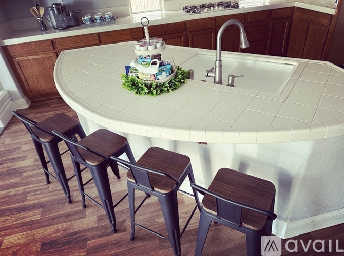 A kitchen with a white counter and bar stools.