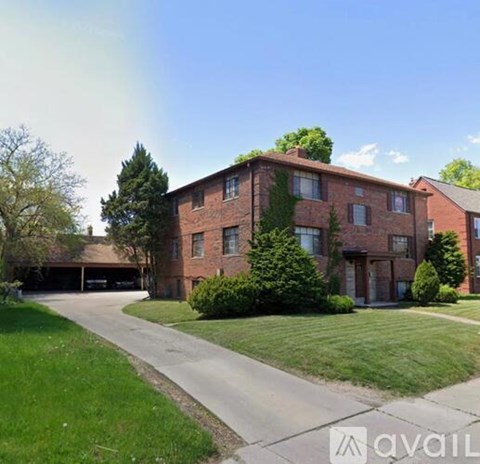 A brick apartment building with a driveway in front.