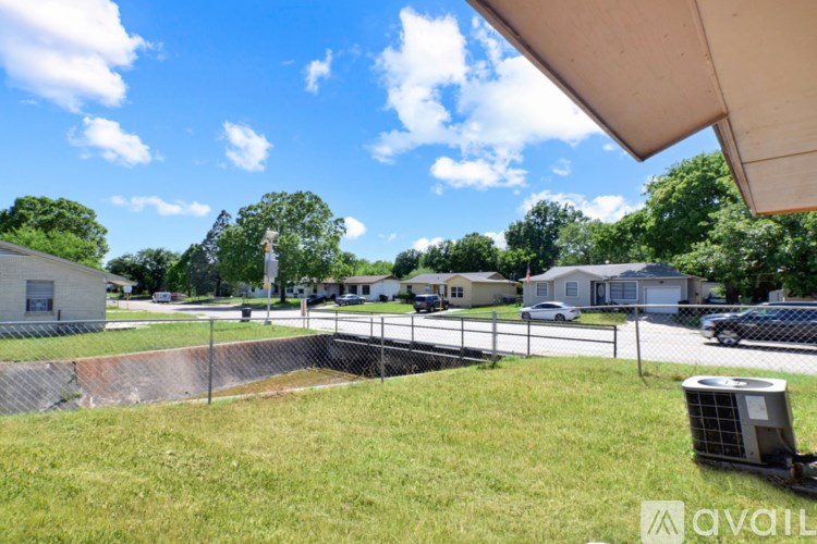 A grassy area with a fence and a house in the background.