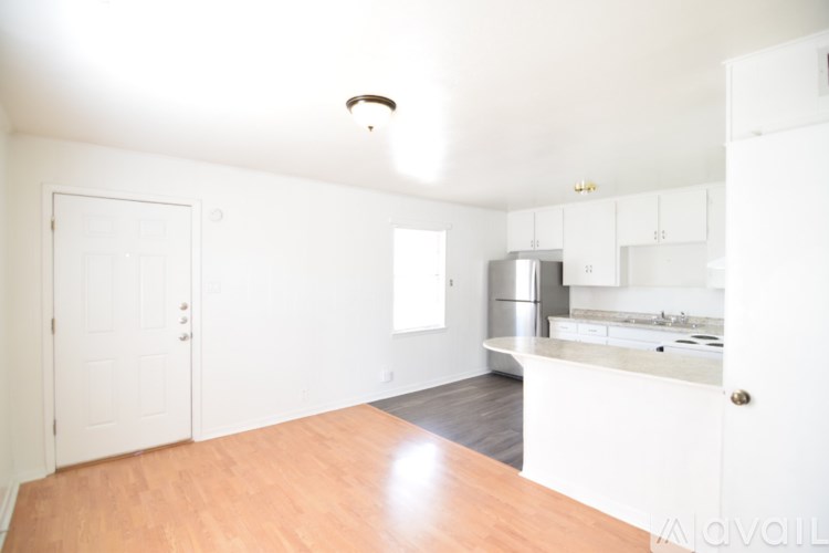 A kitchen with white cabinets and a wooden floor.