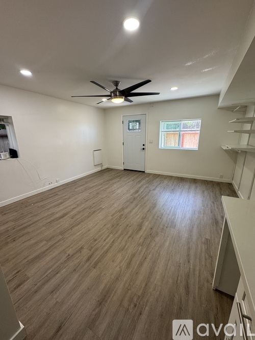 A room with a ceiling fan and wooden flooring.