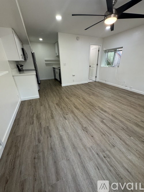 A room with a ceiling fan and wooden flooring.