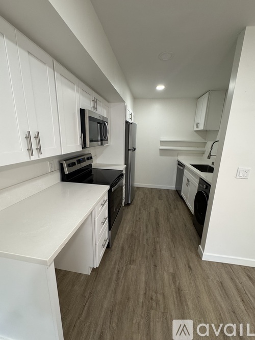 A kitchen with white cabinets and a black stove top oven.