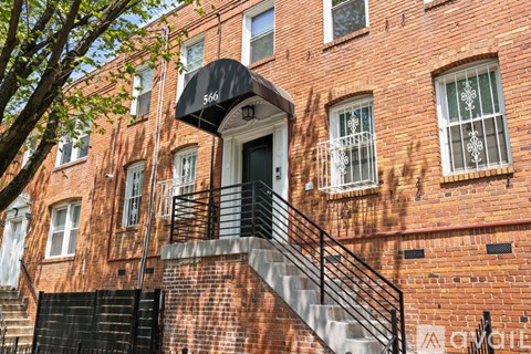 A brick building with a black awning and a staircase leading to the entrance.