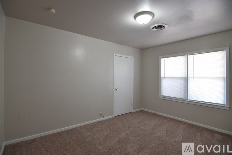 A room with a carpeted floor, a ceiling fan, and two windows.