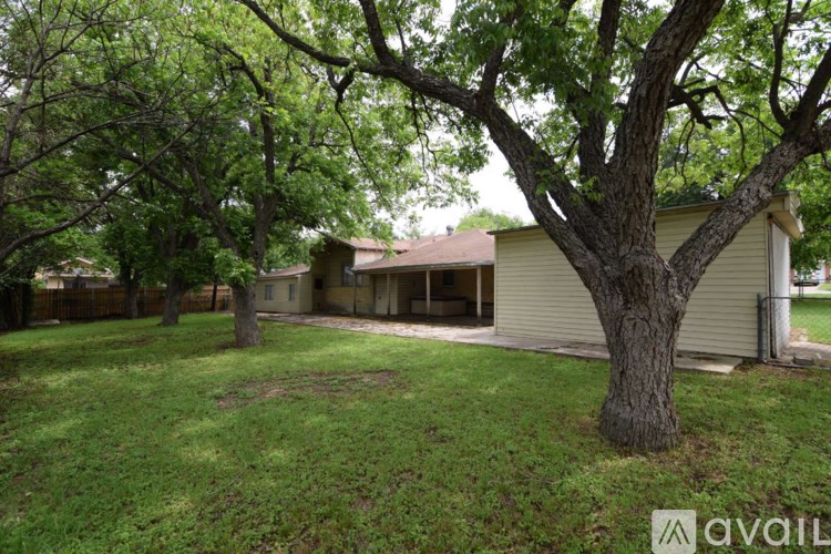A tree in a yard with a house in the background.
