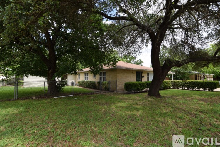 A house is surrounded by a grassy area and trees.