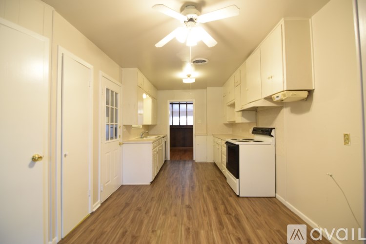 A kitchen with white cabinets and a wooden floor.