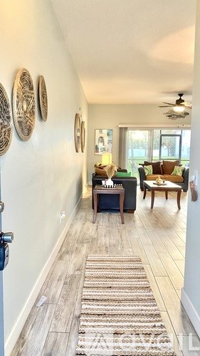 A hallway with a rug on the floor and a ceiling fan.