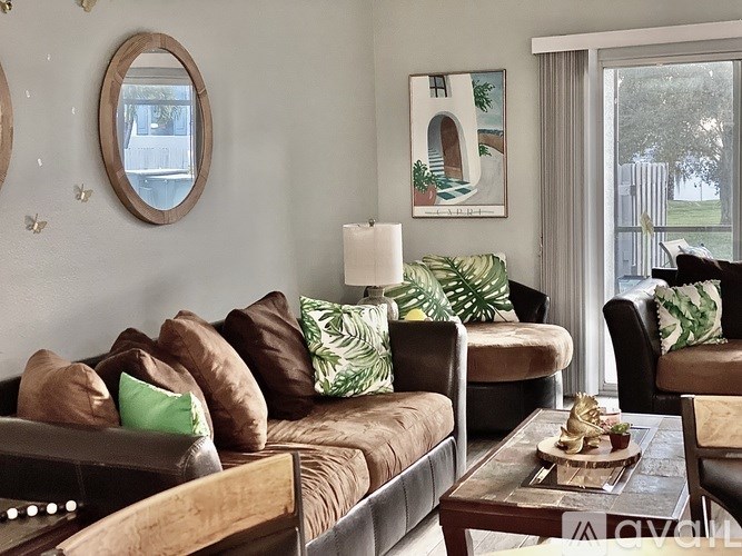 A living room with a brown couch and a painting on the wall.