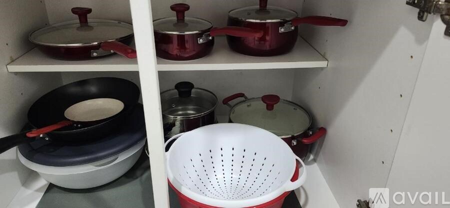 A kitchen pantry with a white shelf holding pots and pans.
