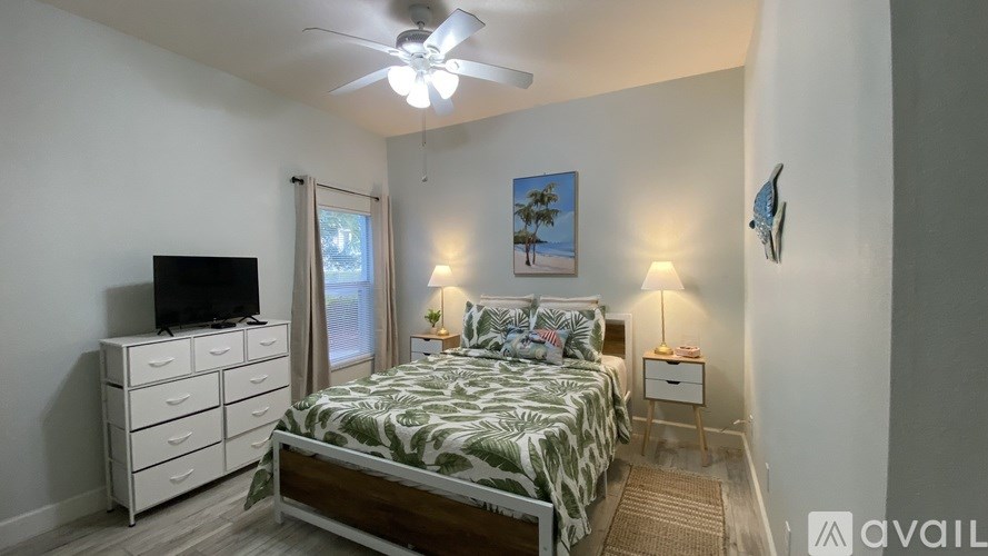 A bedroom with a bed, dresser, and ceiling fan.