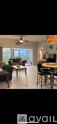 A living room with a couch, chairs, and a ceiling fan.