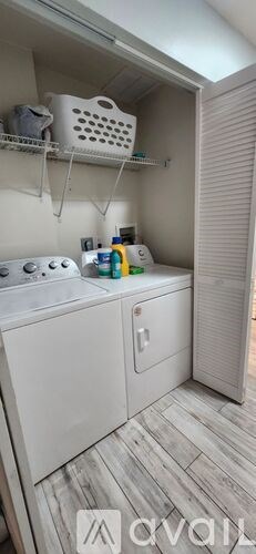 A small, white, compact kitchen with a washing machine and a shelf above it.