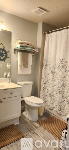 A bathroom with a toilet, sink, and shower curtain.