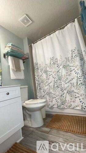 A white toilet in a bathroom with a shower curtain.
