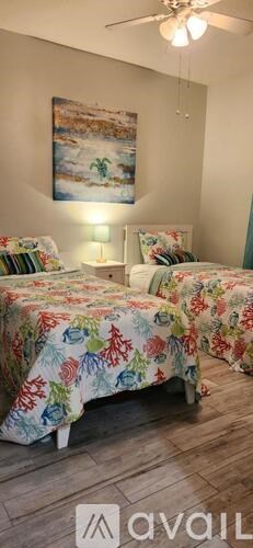 Two beds with floral bedspreads in a room with a painting on the wall.