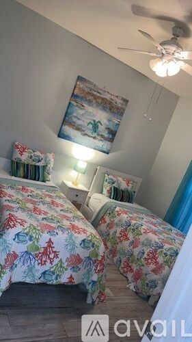 Two beds with floral bedspreads in a room with a ceiling fan.