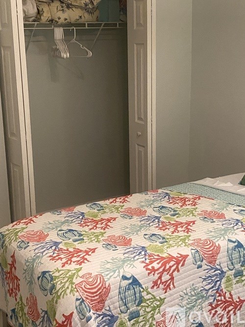 A bed with a floral print is in a room with a white door.
