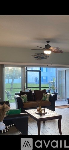 A living room with a brown couch and a ceiling fan.