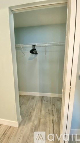 A white closet with a black hanger on the rod.