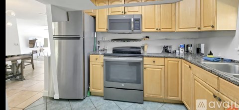 A kitchen with wooden cabinets and a stainless steel refrigerator.