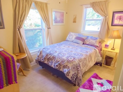 A bedroom with a bed, a lamp, and a window with curtains.