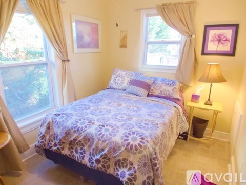 A bedroom with a bed covered in a purple and white patterned bedspread.